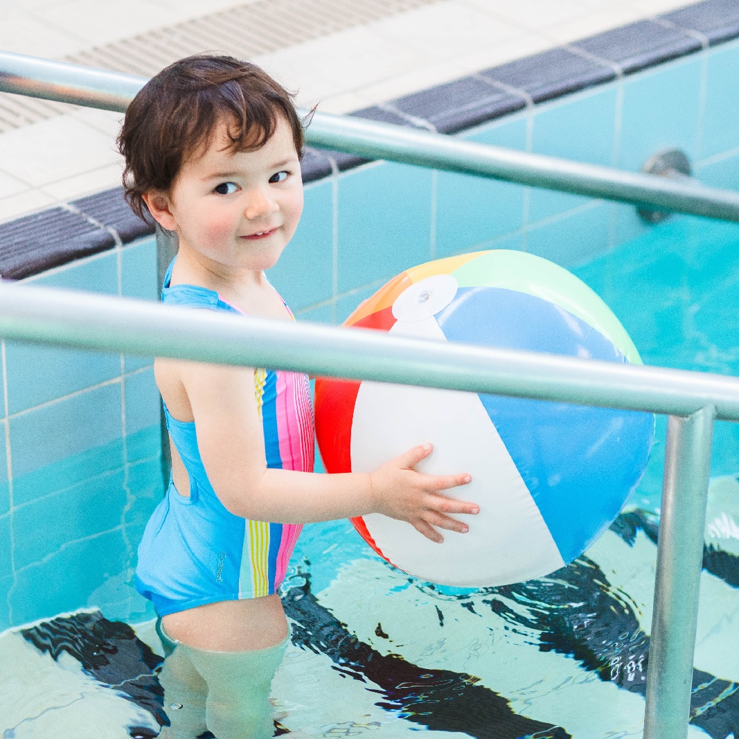 Toddler with ball in pool